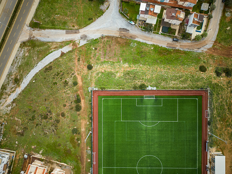 aerial view green football field, streets and buildings. Football stadium sized to FIFA standards. Drone shooting.