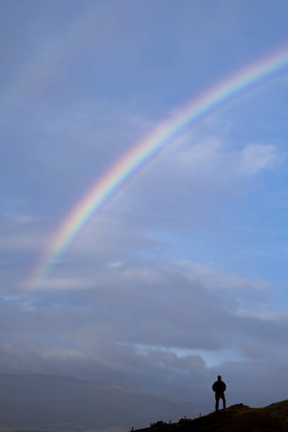 istock Man on the mountain watching the rainbow in the sky. 1460603288