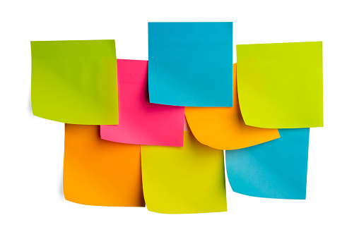 Set of multicolored office sticky notes with curled corners pasted on the wall. Minimalistic concept of organizing cases, reminders, messaging.