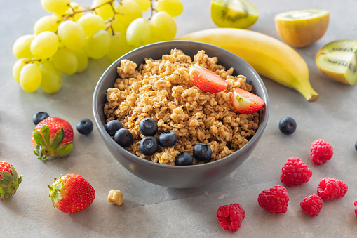 Plate with homemade granola and various fruits for cooking tasty and healthy breakfast on a light background