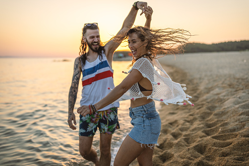 Happy young couple having fun by the sea, dancing and enjoy in their summer vacation.