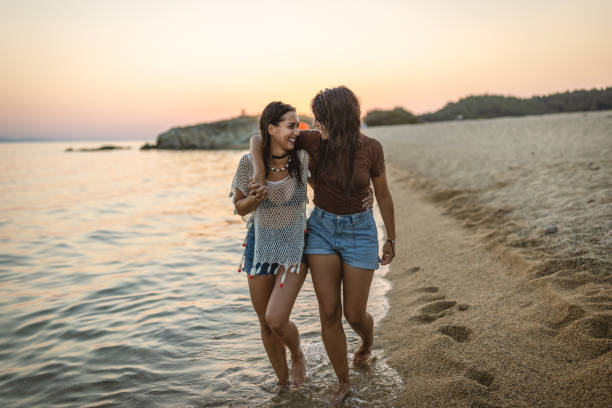 Photo of female friends walking at the beach and enjoying their summer vacation.
