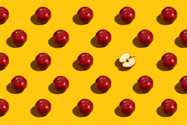 istock Bright red apples with one cut in half on yellow background 1460613294