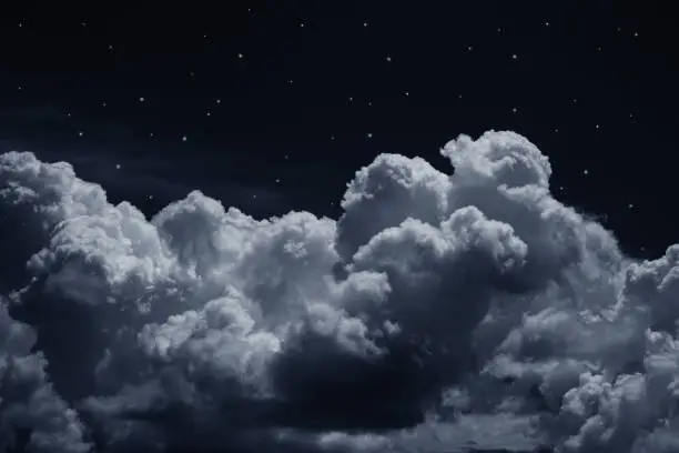 Photo of Black dark blue night sky with stars. White cumulus clouds. Background for design.