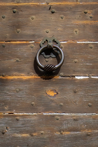 An iron door knocker on an old wooden door.