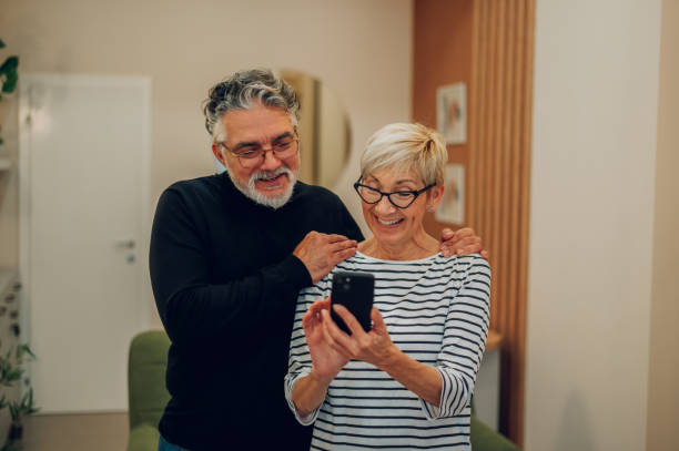 自宅で一緒にスマートフォンを使う老夫婦 - document lifestyles senior couple female ストックフォトと画像