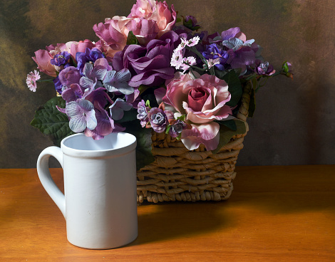 assorted flowers in a basket  with a coffee cup