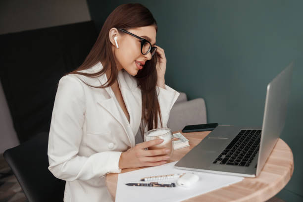 istock Beautiful young woman working on laptop computer, drinking coffee. 1460617515