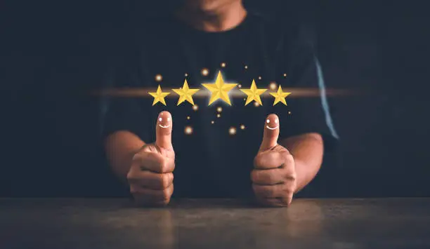 Photo of Customer experience satisfaction concept. Hand of client thumb up positive emotion smile face icon and five star. Standardization and quality in products and services. Excellent services rating.