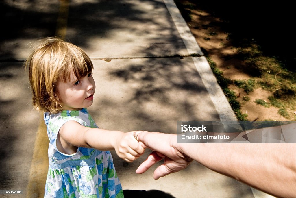 Young child holding the hand of an adult A three year old child playing. Adult Stock Photo
