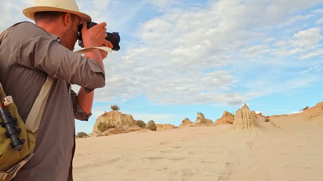 Close up of man taking photos with camera in the dry arid landscape of outback Australia