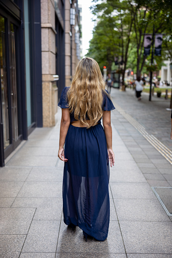 Rear view of woman walking in city - Full length