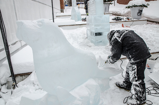 Man sculpting ice and making a seal during day of winter in Quebec city. This is in preparation of the International Winter Carnaval in February.