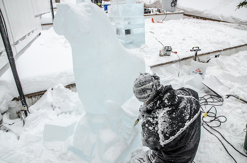 Man sculpting ice and making a seal during day of winter in Quebec city. This is in preparation of the International Winter Carnaval in February.