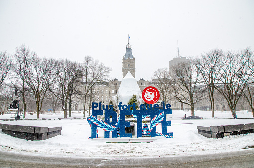 Quebec city Winter Carnaval slogan in front of the Quebec Parliament during winter day.\nIt says in slang french canadian: Stronger than cold.\nThere is the traditional arrow sash around the slogan with the head of the Bonhomme Carnaval snowman.\nThe Carnival generally happens on the first week of February,