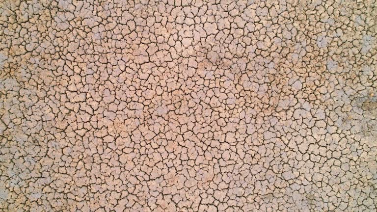 Slow zoom out of dry cracked creek bed pattern from severe drought in the dry arid landscape of outback Australia