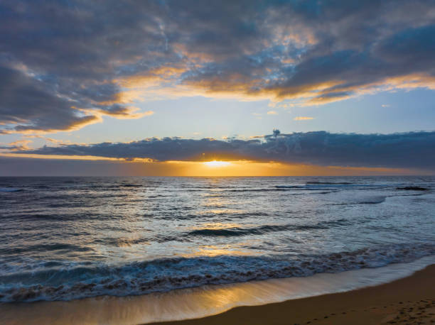 istock Sunrise over the ocean with clouds and sunburst 1460625592
