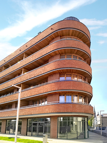 Modern red brick apartment building with balconies along the length and a rounded corner