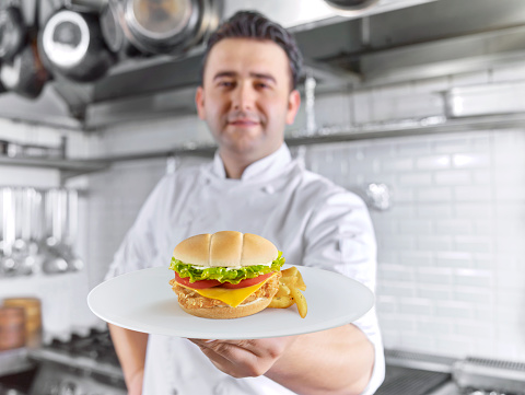 Chef serving a gourmet burger in a commercial kitchen