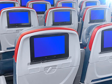 Airplane seats with blank  tv screens in an airplane cabin