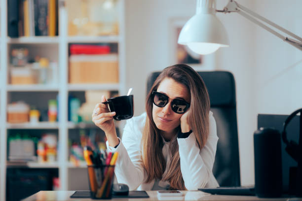 Hangover Woman Drinking Coffee Wearing Sunglasses in the Office Sleepy businesswoman working after a night of partying hangover stock pictures, royalty-free photos & images