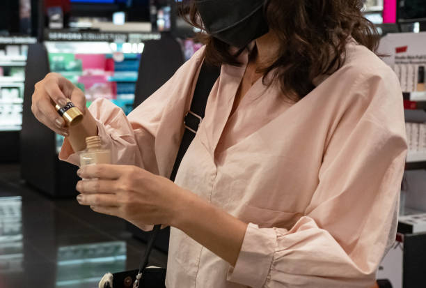 istock Asian Woman Opening Foundation Sample Bottle at Store 1460646933