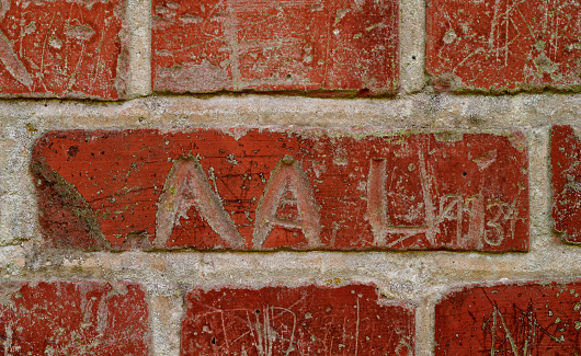 Very old and abandoned school with brick walls marked by letters, dates, and signs made by school children.
Old red brick wall grunge texture. Old cracked bricks wall with a weathered surface. Brick wall background, copy space for design and text. Vintage brick wall.