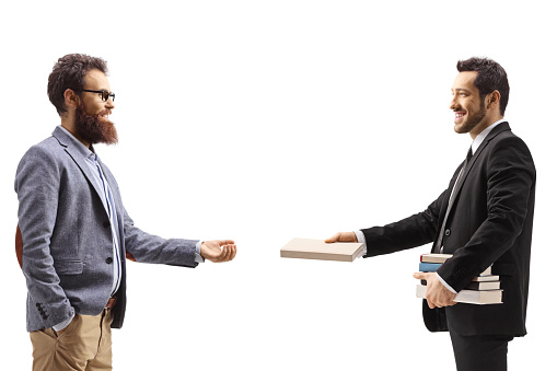 Profile shot of a businessman giving a book to a bearded man isolated on white background