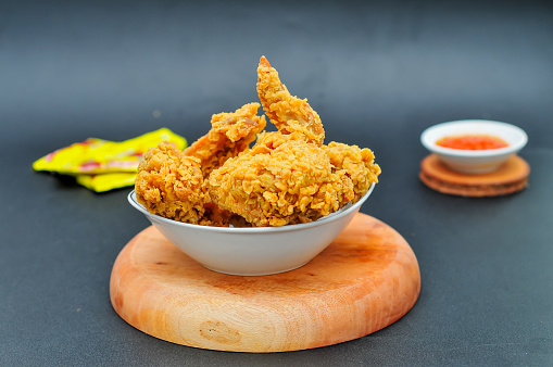 Fried chicken served in a bowl is white on a dark background