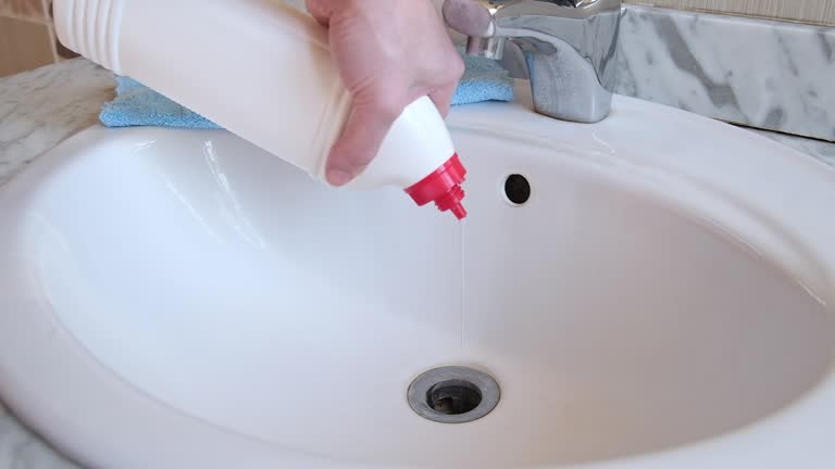 Removal of blockage in the sink, the hand of a man with a bottle of a special remedy with granules. Clean the blockages in the bathroom with chemicals.