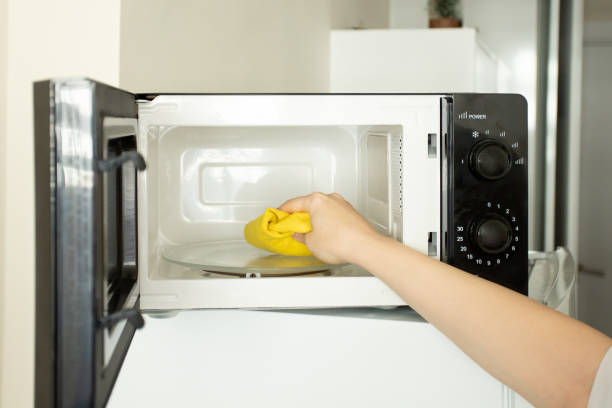microwave washing, woman cleaning a dirty oven stock photo