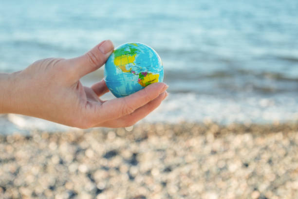 istock Global environmental protection earth concept, ecology development, renewable, sustainable resources, hand with globe on sea background 1460664056