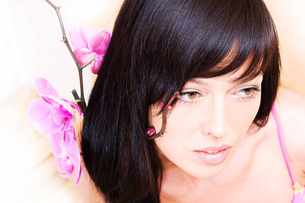 Beautiful asian girl with orchid. Low DOF, focus on eyes