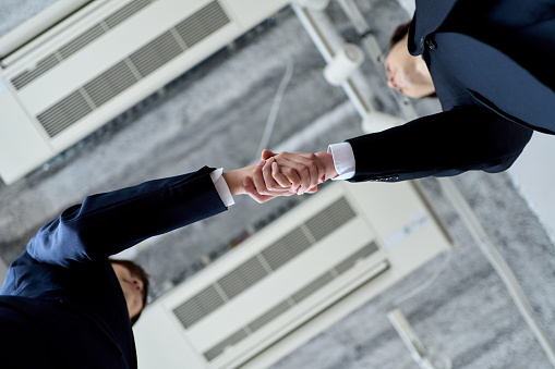Male and female Asian business people shaking hands