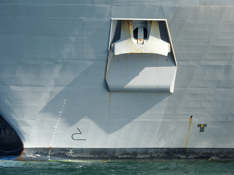The bow of HMAS Canberra docked at Garden Island in Sydney Harbour with her anchor.  The waterline displacement is marked to 10.8 metres.   She is one of two Canberra Class Amphibious Assault Ships in the Royal Australian Navy.  This image was taken from Mrs Macquarie's Chair on the sunny afternoon of 28 January 2023.