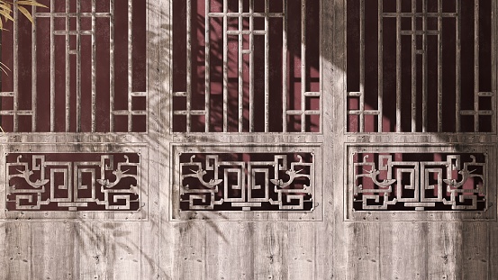 Old, antique traditional Chinese carved patten door with beautiful wood grain in morning sunlight, bamboo leaf shadow and red maroon wall for Asian exterior design and architecture background 3D