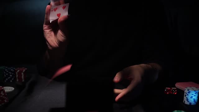 Bearded man plays poker in a casino. The person wins and effectively throws the cards on the table. Slow motion.