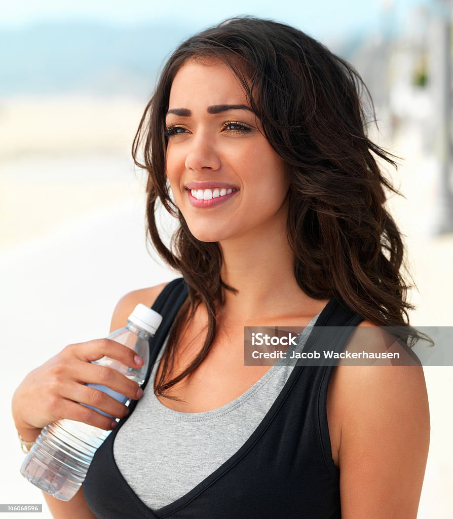 Primer plano de una mujer joven feliz sosteniendo una botella de agua - Foto de stock de 20-24 años libre de derechos
