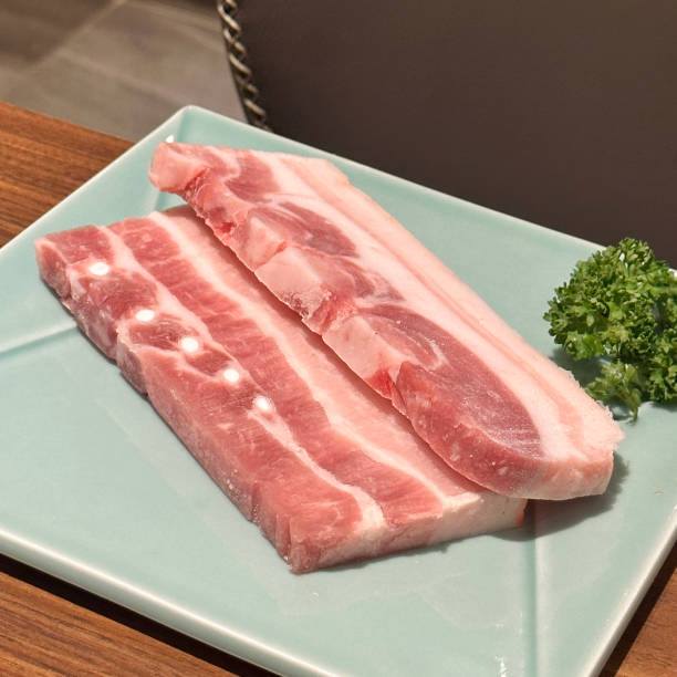 istock Grilling pork belly meat on a round BBQ net in restaurant for eating. 1460689293