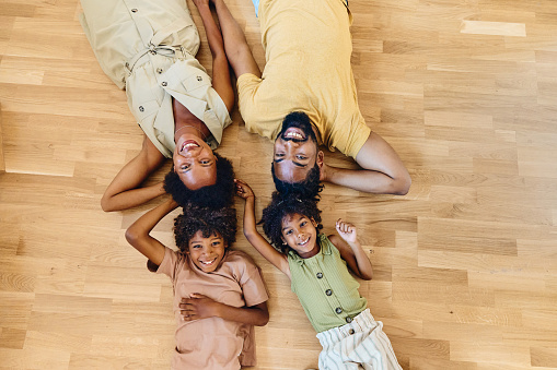 High angle view of happy African American family enjoying while resting on floor at home and looking at camera. Copy space.