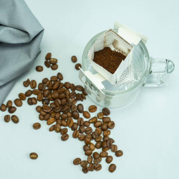 istock ground coffee, a bag for coffee drops and a transparent mug on the table. Drop coffee on a gray background with coffee beans. coffee is prepared by drip brewing using cook. 1460692602