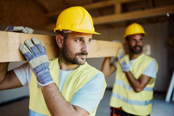 Manual workers carrying wood plank at construction site. stock photo