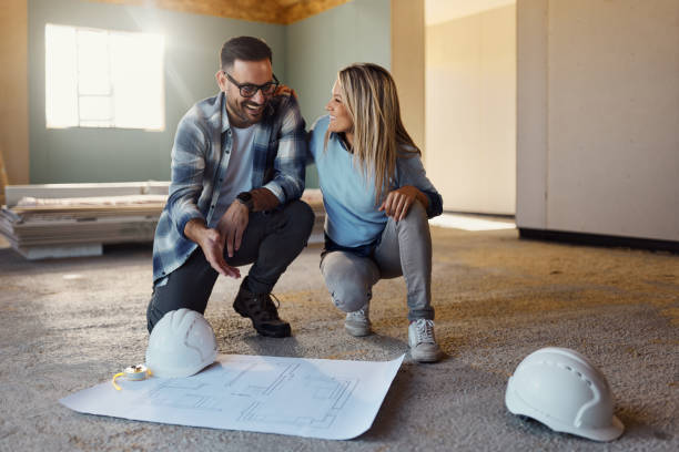 istock Happy couple talking while examining blueprints at construction site. 1460693144