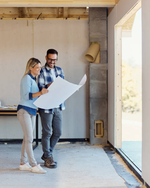 Happy couple reading blueprints of their developing house.