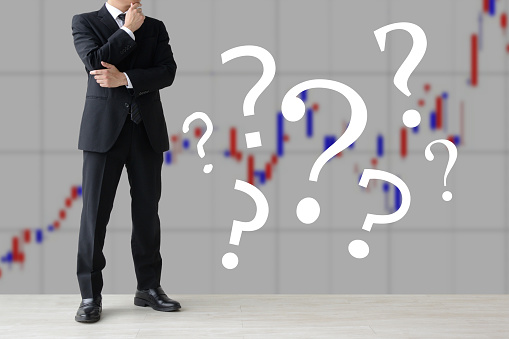 Thinking investor surrouded by question marks