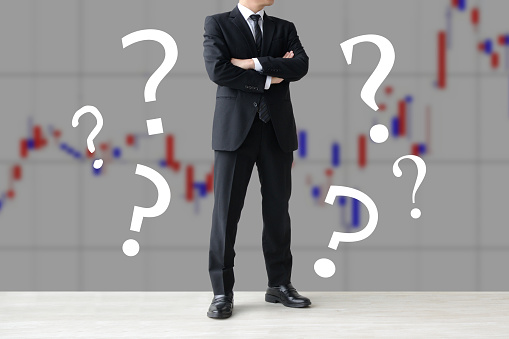Thinking investor surrouded by question marks