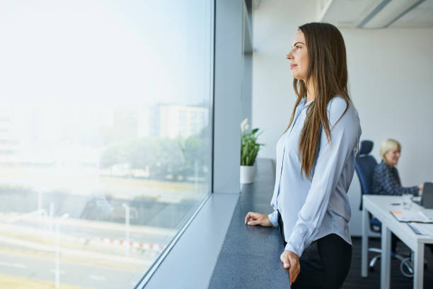 istock Businesswoman standing in office looking through the window 1460698647