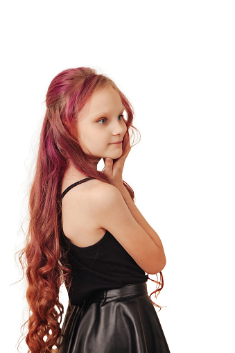 Studio shot of pensive little girl model with red long hair isolated empty white background, looking away. Stylish thoughtful child girl posing shooting. Fashion style concept. Copy text space for ad