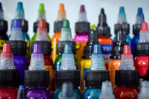 A close-up shot of rows of colorful tattoo inks in plastic bottles