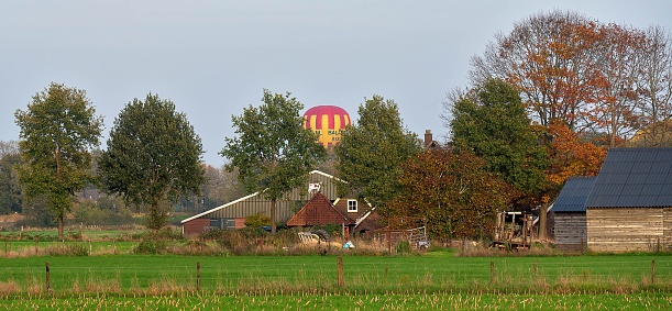 A panoramic shot of a house and a hot air balloon in a field